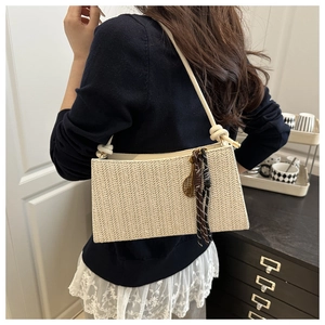 Detail of straw woven shoulder bag with leather strap and metal key tassel charm