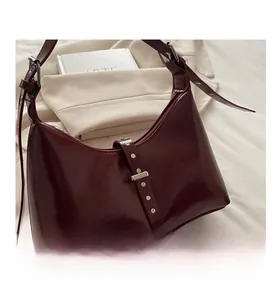 Détail du sac hobo en cuir bordeaux foncé avec rivets métalliques et bandoulière réglable