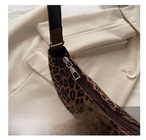 Detail view of the smooth silver zipper closure on a leopard print suede dumpling bag