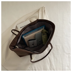 Top view of spacious brown matte tote bag interior filled with daily essentials