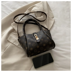 Macro shot of dark brown monogram pattern and gold twist lock on the luxury tote bag