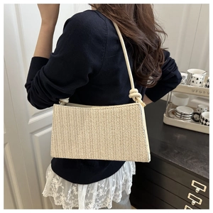 Detail of hand-woven straw shoulder bag with V-shaped texture and knotted strap