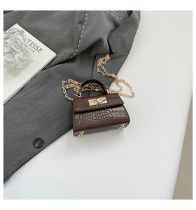 Detail of dark brown croc-pattern mini bag with gold chain strap on grey blazer
