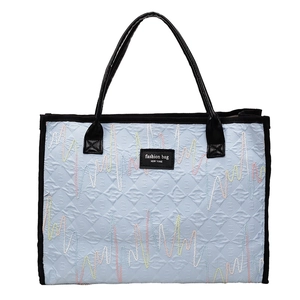 Large light blue quilted tote bag with colorful embroidery and black handles for women