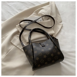 Detail of dark brown monogram tote bag with cylindrical handles and adjustable strap