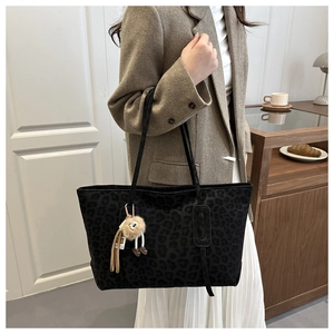 Detail of high-capacity leopard print tote bag with plush charm on a slim shoulder strap
