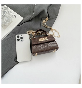 Detailed macro view of dark brown croc-embossed mini bag with golden metal hardware