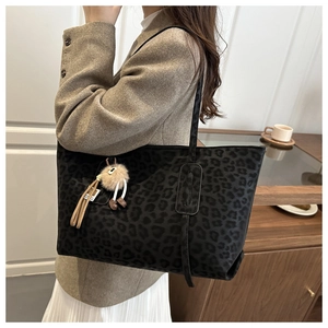 Detail of black leopard print tote bag with soft texture and stylish tassel charm