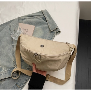 Dettaglio della borsa a mezzaluna in nylon beige con logo rotondo e tracolla larga