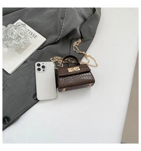 Macro detail of dark brown croc-embossed mini bag with gold hardware and phone for scale