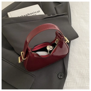 Interior detail of wine red patent leather mini bag with lipstick and earbuds inside