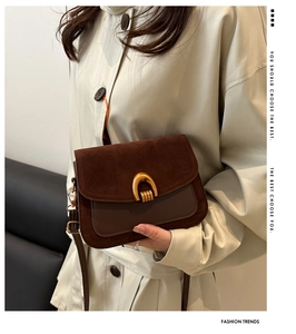 Detail of vintage saddle bag with brown suede flap and golden U-shaped metal buckle