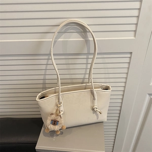 Minimalist beige leather tote bag with long straps and plush animal charm for daily commute