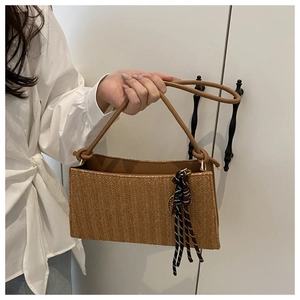 Detail of retro woven tote bag with a brown finish and stylish tassel accessory