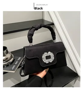 Detail of black suede handbag featuring a sparkling crystal buckle and pleated handle