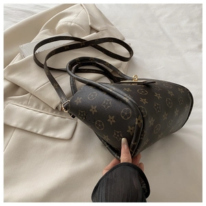Detailed shot of retro brown patterned bucket bag with gold twist lock on light blazer