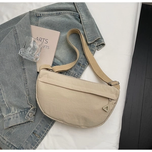 Dettaglio della borsa a mezzaluna beige con tracolla regolabile e tiretto della zip a triangolo