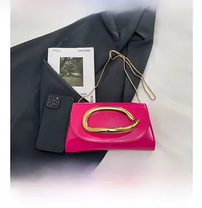 Detail of bright pink patent leather bag with gold circular metal buckle and chain strap