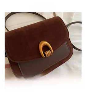 Detail of vintage brown crossbody bag featuring suede textures and gold horseshoe buckle
