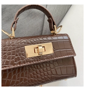 Detailed macro view of dark brown faux crocodile leather texture and golden twist lock