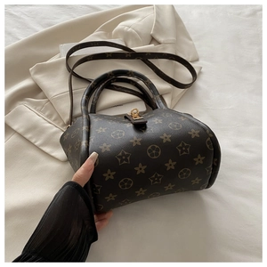 Detail of dark brown star patterned tote bag with gold metal twist lock on beige fabric