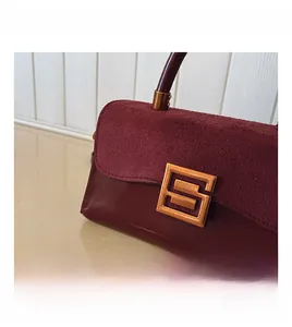 Detail of burgundy shoulder bag with suede flap and gold geometric square metal lock