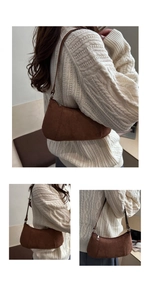 Close-up of a vintage brown suede croissant bag with silver zipper and slim strap