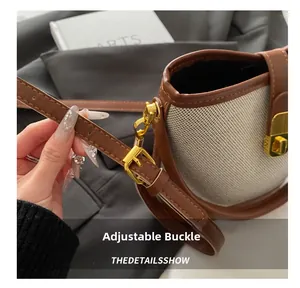 Detail of adjustable metal buckle on contrast canvas and leather bucket bag strap