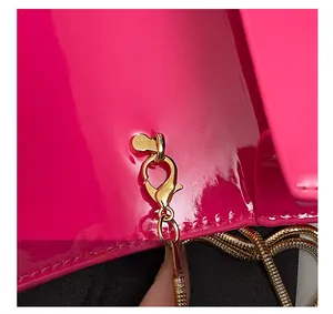 Close-up of golden lobster clasp and snake chain on fluorescent pink patent leather bag