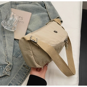 Dettaglio della borsa a tracolla in nylon beige con tracolla larga e fibbia in metallo