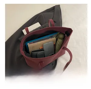 Spacious burgundy suede tote bag showing interior storage for books and umbrella