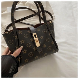 Detail of vintage brown floral tote bag with gold twist lock and smooth leather handle