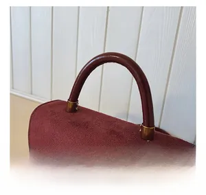 Detail of dark red matte leather handbag with vintage gold F-logo buckle and top handle