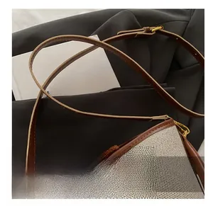 Detail showing the mixed beige knit fabric and brown leather trim with metallic buckle