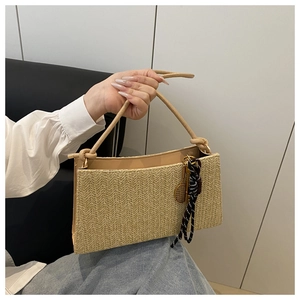 Detail of woven straw shoulder bag with tennis racket charm and striped ribbon