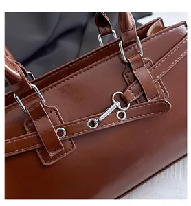 Detailed close-up of dark brown leather handbag with silver metal hardware and straps