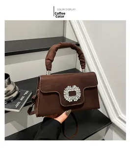 Detail of coffee brown textured handbag with large crystal buckle and pleated handle