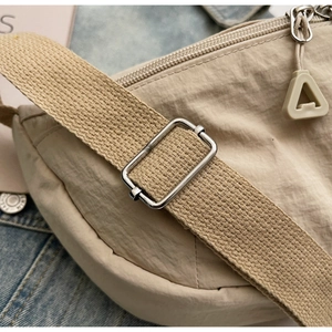 Dettaglio della borsa a tracolla in nylon beige con tracolla regolabile e zip materica