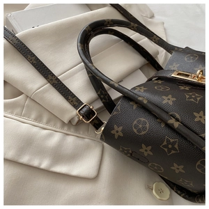 Detail of classic brown monogram tote bag with gold metal buckle and leather handle