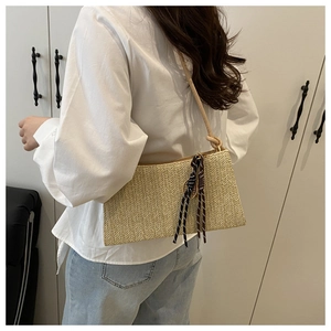 Detail of light beige straw shoulder bag featuring a striped silk scarf and thin strap