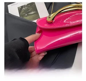 Detail view of pink patent leather bag with precise stitching and golden metal handle