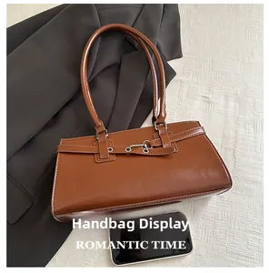 Brown vintage baguette bag detail with metallic buckle and smartphone for size comparison