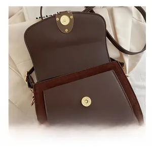 Detail view of the vintage brown leather shoulder bag with gold cylindrical metal clasp
