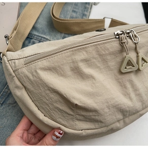 Dettaglio della borsa a mezzaluna in nylon beige con doppia zip e tracolla regolabile