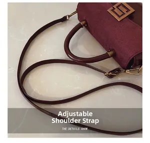 Detail of burgundy leather handbag with adjustable strap and vintage gold buckle