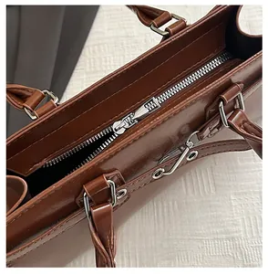 Detail of silver zipper closure and metallic hardware on brown leather tote bag