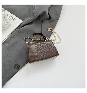 Macro view of brown faux crocodile leather texture and golden metal feet on mini bag