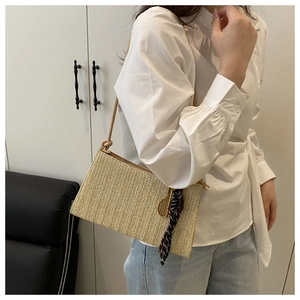 Detail of beige straw crossbody bag with tennis racket charm and checkered silk scarf accessory