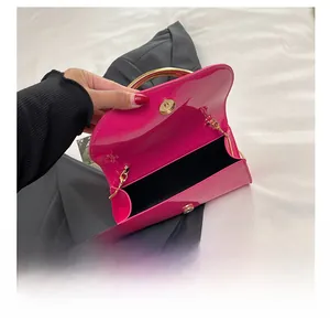 Detail view of pink patent leather handbag with gold metal handle and chain strap