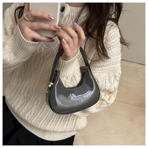 Detail of a mini glossy patent leather half-moon handbag with gold metal hardware